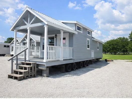 Modern luxury tiny home exterior featuring light gray horizontal siding, a covered front porch with white railings and columns, and a metallic gabled roof, showcased alongside a bright, open-concept interior with vaulted ceilings, white shiplap walls, a modern kitchenette, and cozy gray furniture, perfect for minimalist living and innovative small space architectural design.