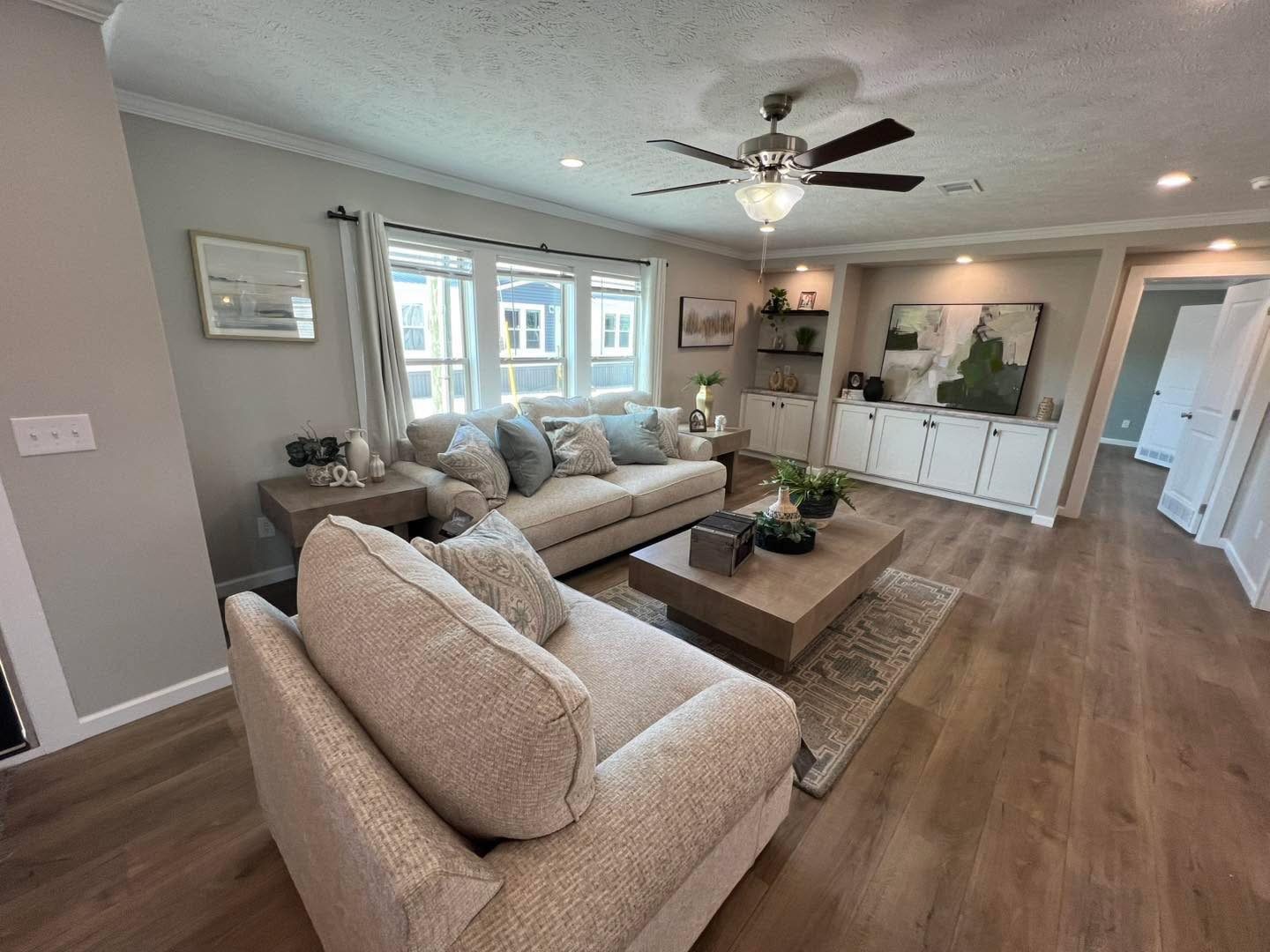 Modern luxury double-wide manufactured home for sale featuring a triple-gabled front exterior with white horizontal siding, forest green accent panels, and rustic stone skirting, complete with a natural wood entry staircase and expansive multi-pane windows for a sophisticated, high-end, and move-in ready turn-key residential property.