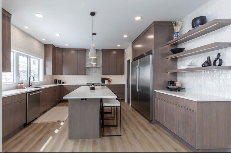 Modern kitchen with light wood flooring, dark wood cabinets, a long island with stool seating, pendant lights, open shelving, and stainless steel appliances.