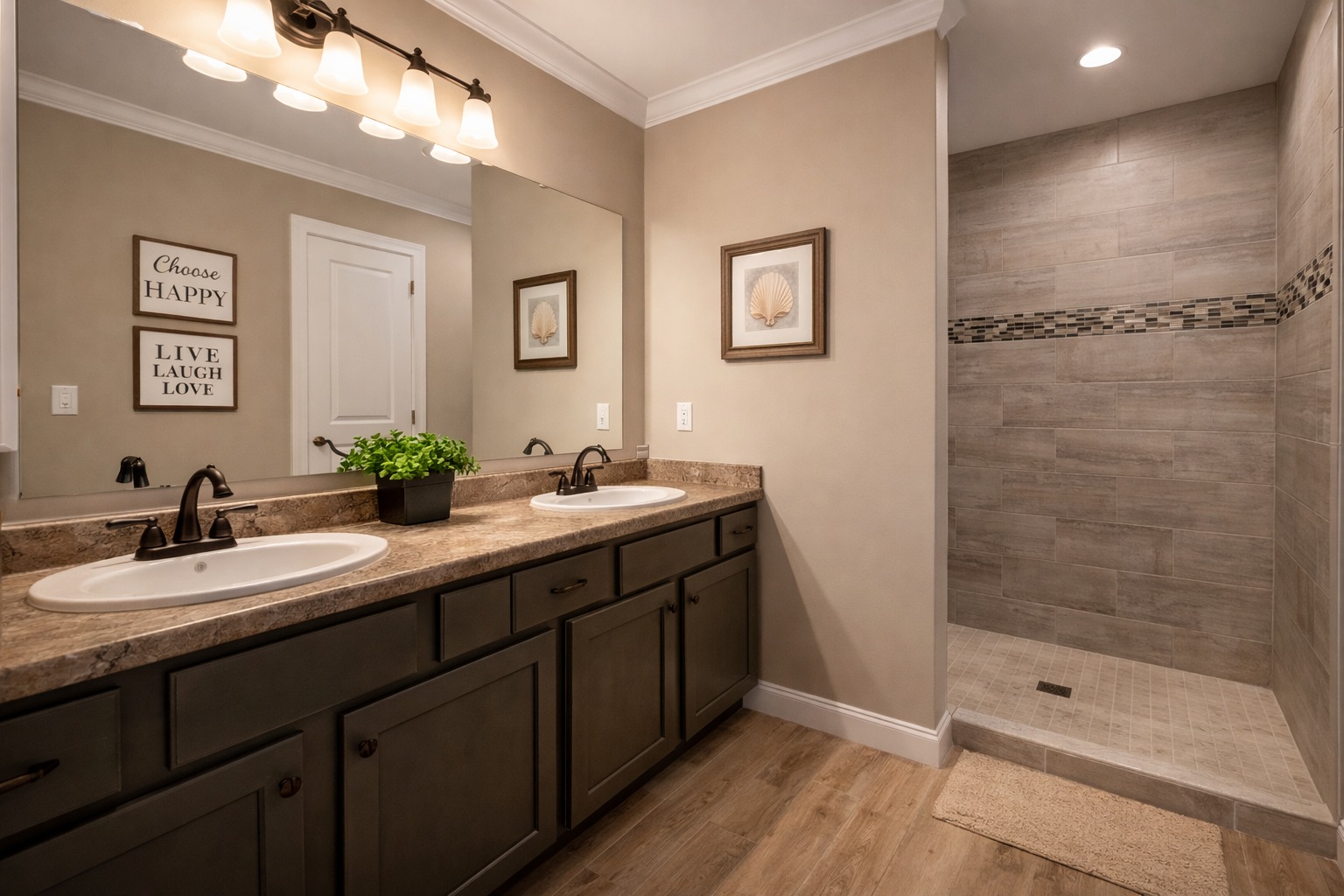 Modern bathroom with dual sinks, dark wooden cabinets, and beige countertop. Large mirror reflects warm lighting. Open shower on right. Cozy and elegant.