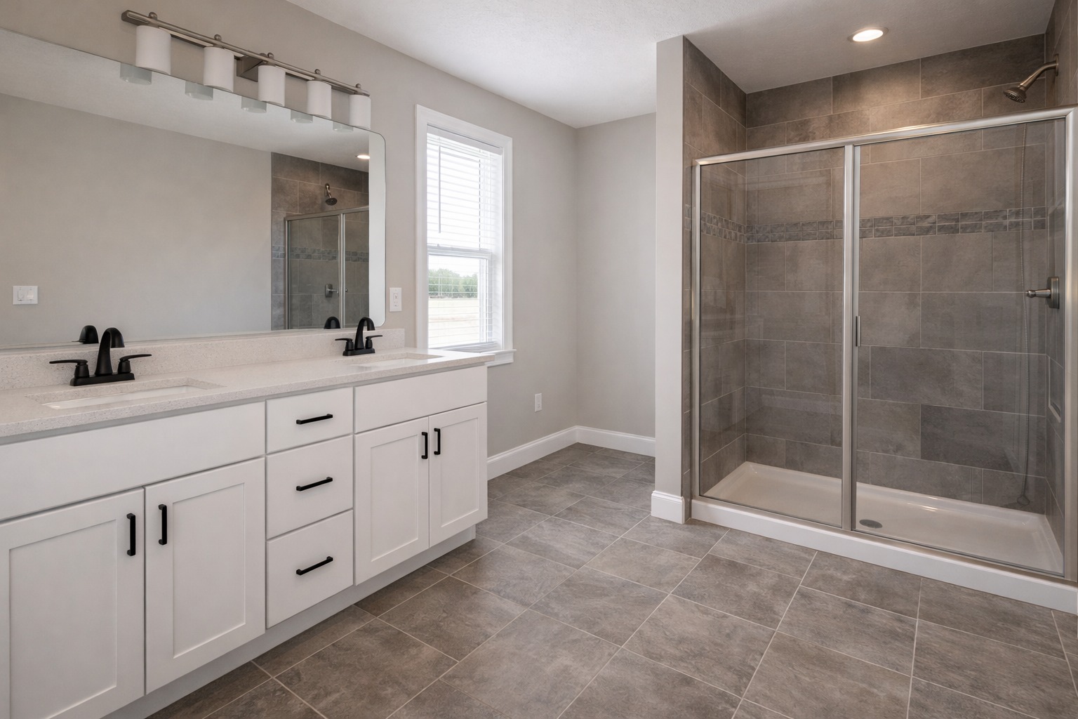 A modern bathroom featuring a large glass shower with gray tiles, a double-sink white vanity with black fixtures, and a wide mirror, evoking a clean and elegant tone.