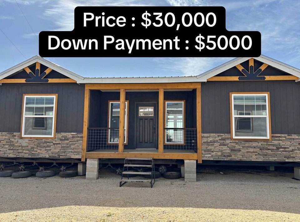 Modular home with a stone façade and wooden trim. Price: $30,000, Down Payment: $5000. Front porch with steps, tire foundation, under a blue sky.