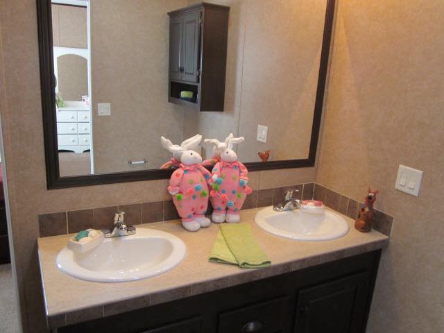 Family bathroom with dual sinks, each with plush bunny decorations in pink polka-dot attire. A green towel lies between them, adding a playful touch.