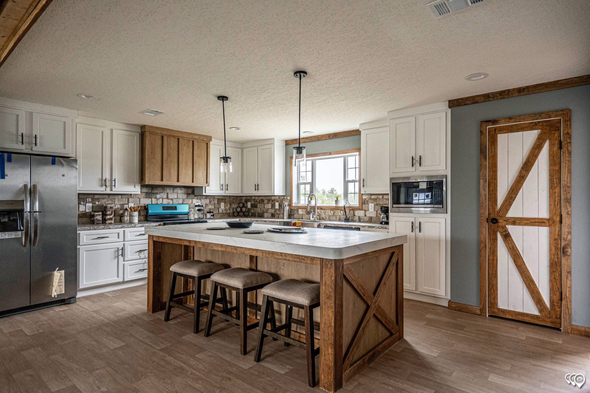 Rustic kitchen features a large island with three stools, pendant lights, and modern appliances. Wooden accents with white cabinets create a cozy feel.