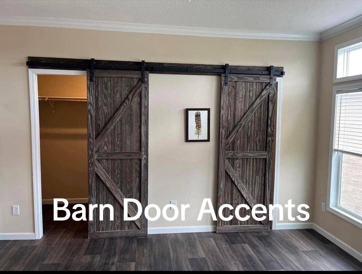 Barn doors with rustic wood finish slide open to reveal a closet. A small feather art piece hangs between the doors, with text "Barn Door Accents" overlayed.