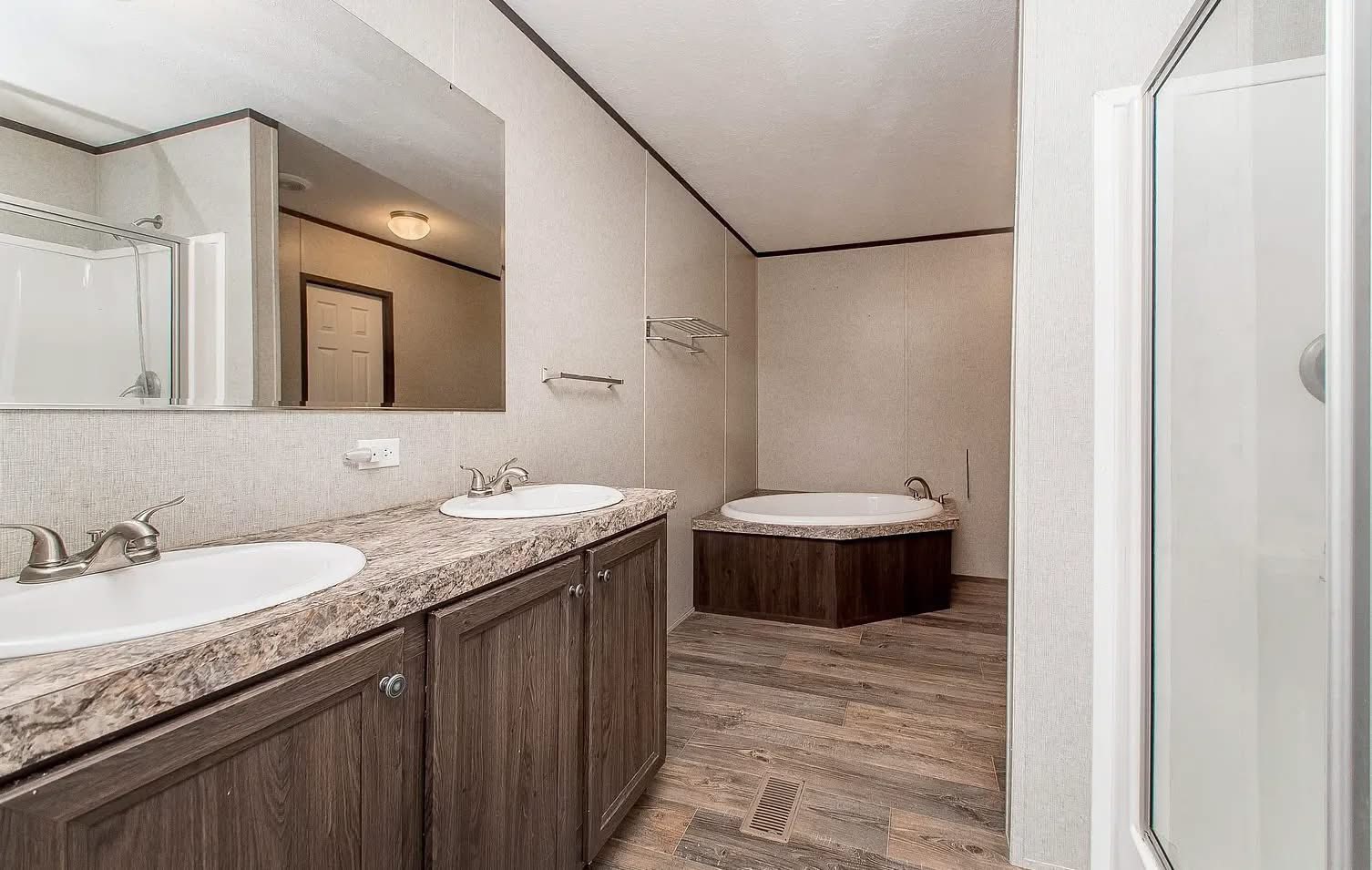 Spacious bathroom with dual sinks and marble countertop. Features a large mirror, corner jacuzzi tub, and a separate shower. Modern, clean design.